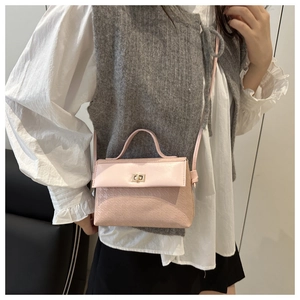 Detail of light pink crossbody bag with embossed texture and gold metal turn-lock closure