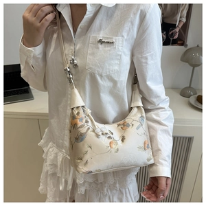 Floral bird embroidery silk underarm bag worn by model in a modern minimalist setting