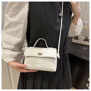 Detail of white embossed leather handbag with golden twist lock and adjustable shoulder strap