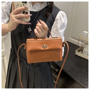 Detailed view of caramel brown crossbody bag with unique textured panel and gold twist lock
