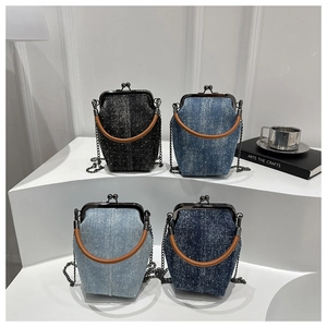 Detailed shot of four denim crossbody bags with rhinestones and round handles on a white stand