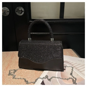 Detail of a black evening bag featuring shimmering rhinestones and a silver chain strap