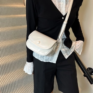Minimalist glossy white crossbody bag with round buckle on a stylish model on stairs