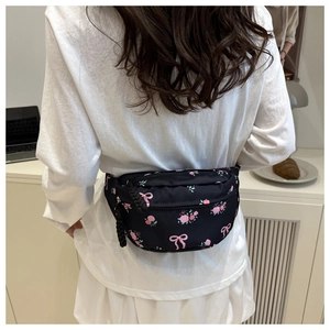 Floral crossbody bag with rose print and woven zipper detail shown on a model