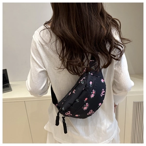 Detail of floral printed nylon fanny pack with rose and bow patterns on black material