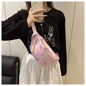 Detailed view of pink floral waist bag with bow print and rose pattern on crossbody model