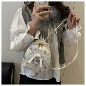 Detail view of mini backpack featuring cartoon patterns and elegant ribbon bow detail