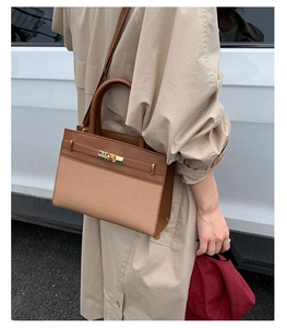 Detail einer Handtasche aus braunem Leder und beigem Canvas mit Metalldrehverschluss