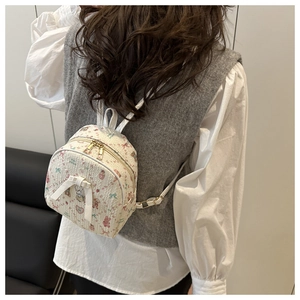 Detail of mini backpack featuring cartoon bear prints and a large white silk bow decoration