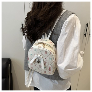 Back view of a mini beige canvas backpack with bear prints and a white decorative bow