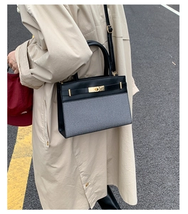 Detail einer trendigen zweifarbigen Umhängetasche mit goldenen Beschlägen am Trenchcoat