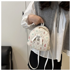 Detail of mini backpack with cartoon bear prints and decorative white bow and heart charm