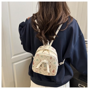 Close-up of white mini backpack with cartoon prints on model showing its compact size