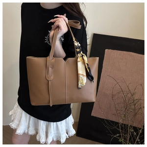 Detail of brown leather tote bag with elegant floral scarf and spacious interior