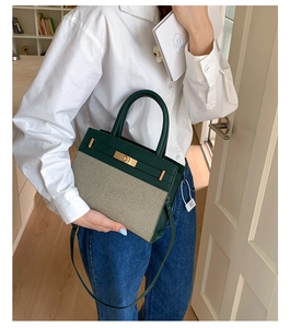 Detail der Handtasche aus dunkelgrünem Leder und beigem Canvas, getragen von einem Model