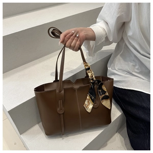 Dettaglio della borsa tote marrone scuro con cuciture fini e sciarpa di seta vintage decorativa