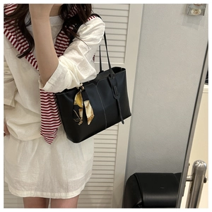Detail of black tote bag with white stitching and decorative silk scarf accessory