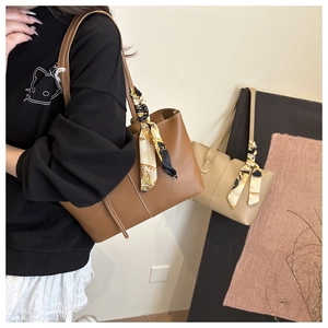 Detail of minimalist leather tote bag featuring elegant gold chain print silk scarf handles