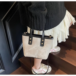 Détail du sac seau en toile avec garniture en cuir noir et rivets dorés