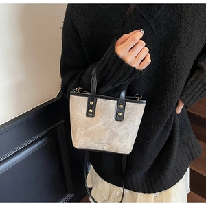 Détail du sac seau taupe avec garniture en cuir noir et rivets dorés décoratifs