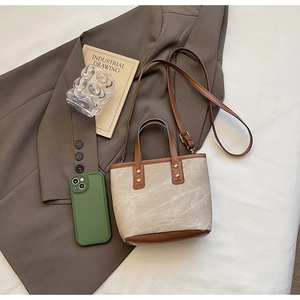 Vue détaillée du mini sac cabas en toile et cuir marron posé sur un blazer marron