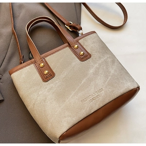 Détail du sac à main en toile et cuir avec rivets dorés et logo gravé élégant
