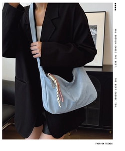 Detail of sky blue large hobo bag with colorful tassel and wide shoulder strap