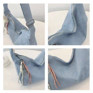 Detail view of light blue canvas hobo bag with tennis racket pendant and silver zipper
