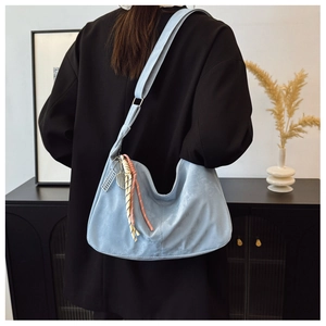 Dettaglio della borsa hobo azzurra in pelle scamosciata con ciondolo da tennis
