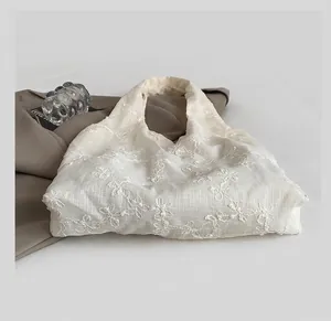 Détail du sac cabas en dentelle blanche avec broderie florale sur tissu mesh