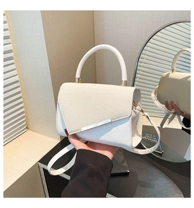 Detail of white PU leather handbag with woven texture and gold-tone metal hardware