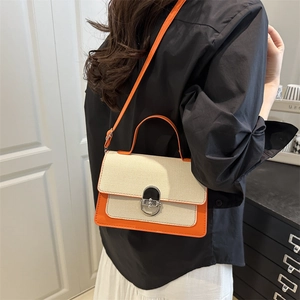 Chic two-tone crossbody bag with orange leather and cream canvas featuring a metal lock