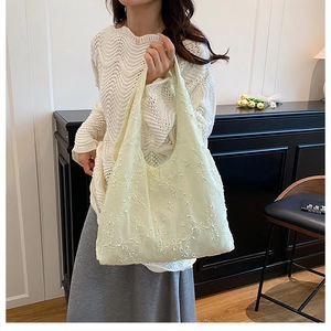 Gros plan détaillé sur la broderie florale crème d'un grand sac cabas en toile