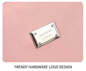 Close-up of silver metal logo plaque on pink oxford fabric tote bag detail