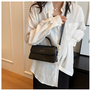 Détail du sac bandoulière en cuir noir mat avec lettrage doré et sangle réglable