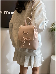Detail eines hellrosa Mini-Rucksacks mit Kettengurt und dekorativer Schleife für Damen