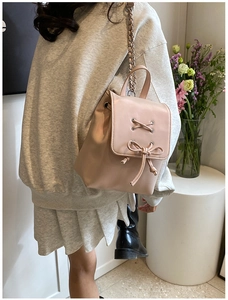 Nahaufnahme eines rosa Mini-Rucksacks mit Schleifen-Detail und Kettenriemen am Model