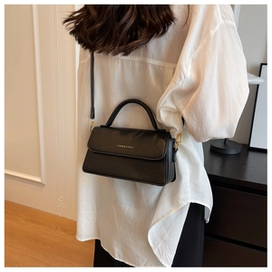 Vue latérale d'un sac bandoulière vintage noir porté par un mannequin dans un intérieur