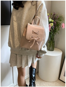 Detail eines rosa Mini-Rucksacks aus Kunstleder mit Schleife und Metallkettenriemen