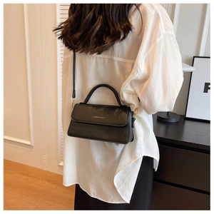 Détail d'un sac à main vintage en cuir noir avec lettrage doré et fine bandoulière élégante