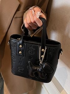 Fashionable black embossed bucket bag with gold chain and leather charm on hand
