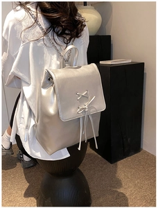 Detail eines silbernen Metallic-Rucksacks mit Schleifen und Kettenriemen am Modell