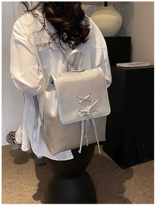 Silberner Metallic-Rucksack mit Schleifendetail und Kettenriemen auf dem Modellrücken