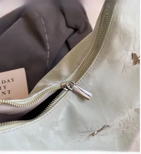 Detail of smooth metal zipper and butterfly ornament on light green textured backpack