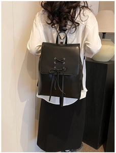 Detailaufnahme des schwarzen Lederrucksacks mit Schleife und Metallkettenriemen am Modell