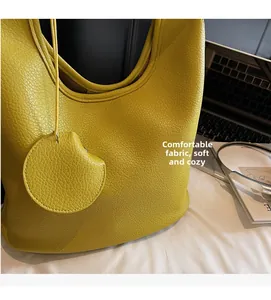Detail of soft yellow lychee grain leather texture on a large capacity hobo bucket bag