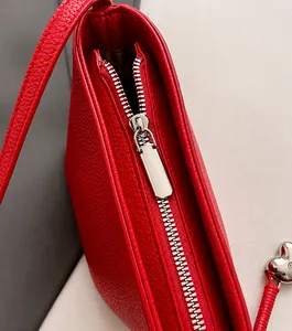 Detail van zilveren rits en rood leer met lychee-patroon op de bucket handtas
