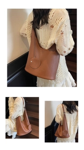 Detailed view of caramel lychee texture leather bucket bag with round charm pendant
