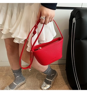 Detail van rode bucket bag van nerfleer met goudkleurig logo en metalen rits