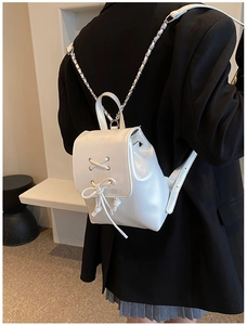 Detail eines weißen Mini-Rucksacks mit Schnür-Schleife und Metallketten-Riemen